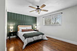 Bedroom featuring an accent wall, dark wood-type flooring, and a ceiling fan