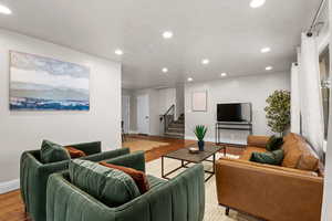 Living room featuring wood finished floors, stairway, and recessed lighting