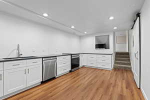 Kitchen featuring a barn door, white cabinets, recessed lighting, stainless steel appliances, and light wood-style flooring