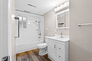 Bathroom with vanity, tub / shower combination, and dark wood-style floors