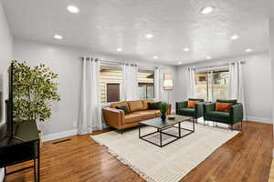 Living area with wood finished floors, a textured ceiling, and recessed lighting
