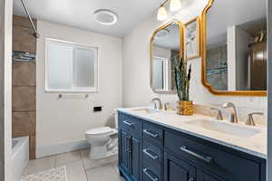 Full bath with double vanity, light tile patterned floors, and washtub / shower combination