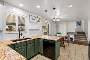 Kitchen featuring green cabinetry, dishwasher, light stone countertops, open shelves, and recessed lighting