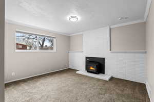 Unfurnished living room with ornamental molding, carpet flooring, and a textured ceiling