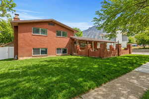 Back of house featuring brick siding, a gate, a chimney, and a mountain view. Photo has been enhanced with A.I.