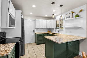 Kitchen featuring green cabinets, stainless steel appliances, white cabinets, open shelves, and hanging light fixtures