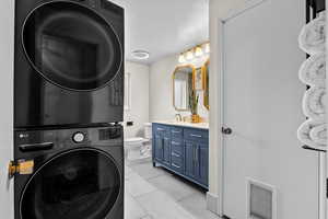 Washroom with stacked washer / drying machine and light tile patterned floors