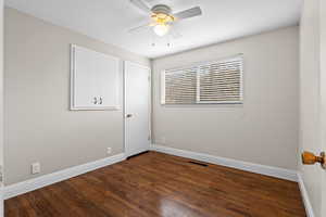 Empty room with dark wood-style floors and a ceiling fan