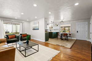 Living area with light wood-style floors, a textured ceiling, and recessed lighting