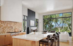 Kitchen featuring light wood-type flooring, light stone counters, tasteful backsplash, a breakfast bar area, and plenty of natural light