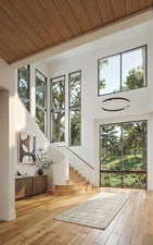 Doorway to outside featuring wooden ceiling, a high ceiling, plenty of natural light, hardwood / wood-style flooring, and stairway