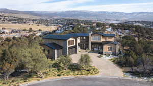 View of front of property featuring driveway, a mountain view, a chimney, stone siding, and a garage