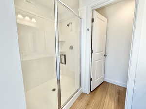 Bathroom featuring a shower stall and wood finished floors