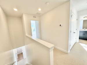 Hall featuring an upstairs landing, light colored carpet, and recessed lighting