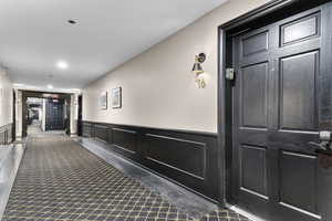 Hallway with wainscoting, a decorative wall, and recessed lighting