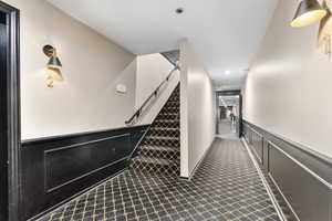 Stairway featuring a wainscoted wall and a decorative wall
