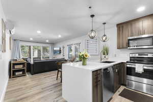 Kitchen with appliances with stainless steel finishes, open floor plan, recessed lighting, light stone counters, and a peninsula