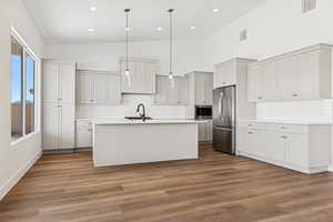 Kitchen featuring hanging light fixtures, decorative backsplash, appliances with stainless steel finishes, a kitchen island with sink, and dark wood-style floors