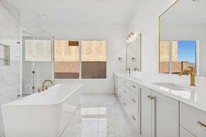 Bathroom with double vanity, a soaking tub, light marble finish floors, and a shower with shower door