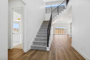 Stairs featuring a towering ceiling, wood finished floors, recessed lighting, and a chandelier