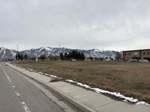 View of asphalt street featuring a mountain view, sidewalks, and curbs