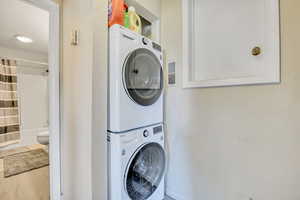 Washroom featuring stacked washer / dryer and a textured wall
