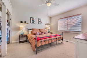 Bedroom featuring light colored carpet, lofted ceiling, and a ceiling fan