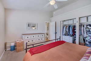 Bedroom featuring light colored carpet, ceiling fan, and high vaulted ceiling