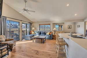 Living area featuring light wood finished floors, high vaulted ceiling, a ceiling fan, and a mountain view