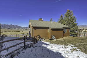 View of side of property featuring a mountain view, a shingled roof, and a chimney
