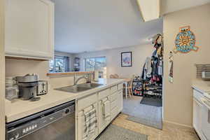Kitchen with dishwasher, light countertops, white cabinetry, and white range oven