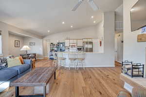 Living area featuring light wood-style flooring, high vaulted ceiling, and recessed lighting