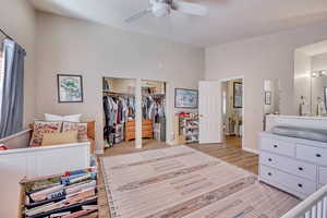 Bedroom with light wood-type flooring, a ceiling fan, and a high ceiling
