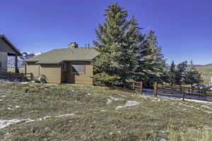 Back of house featuring a mountain view, a shingled roof, and a chimney