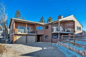 View of front of home featuring a balcony, a chimney, asphalt driveway, and a garage