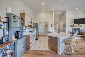 Kitchen with light countertops, open shelves, light wood-type flooring, a towering ceiling, and recessed lighting