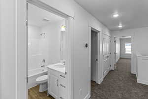Bathroom featuring vanity, shower / washtub combination, and dark wood-style flooring