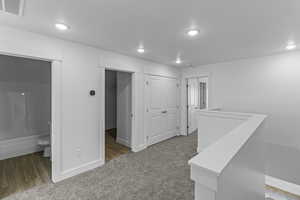 Hall featuring light carpet, an upstairs landing, and recessed lighting