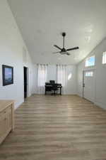 Foyer with light wood finished floors, high vaulted ceiling, a ceiling fan, and healthy amount of natural light