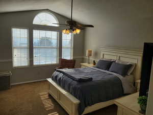 Carpeted bedroom featuring a textured ceiling, a ceiling fan, and lofted ceiling