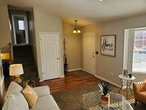 Living area with stairs, a chandelier, dark wood-style flooring, and vaulted ceiling