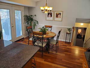 Dining room with dark wood-type flooring, french doors, and a chandelier