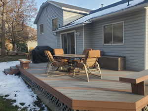 Snow covered deck with a grill and outdoor dining area