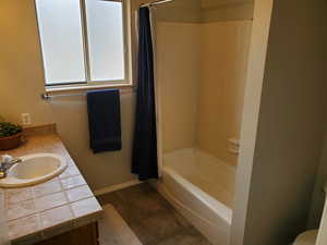 Full bath featuring vanity, shower / bath combination with curtain, and dark tile patterned flooring