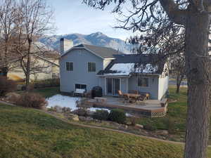 Rear view of house with a lawn, a chimney, outdoor dining area, and a deck with mountain view