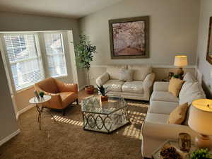 Living area featuring carpet floors and vaulted ceiling