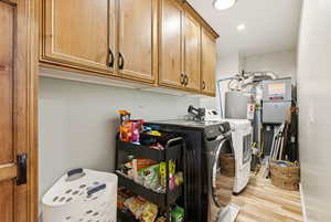 Washroom with separate washer and dryer, cabinet space, light wood finished floors, heating unit, and recessed lighting