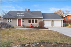 View of front facade featuring a front lawn, a garage, driveway, and roof with shingles