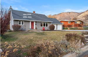 View of front facade with a garage, a shingled roof, a chimney, a front lawn, and driveway
