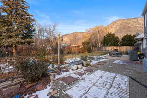 Fenced backyard featuring a patio, a mountain view, a garden, and outdoor dining space